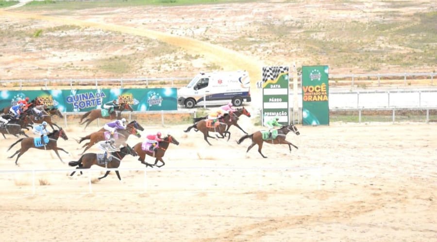 Pelotão de cavalos da Quina da Sorte na reta de 400 metros do Aquiraz, com as placas da Quina ao fundo